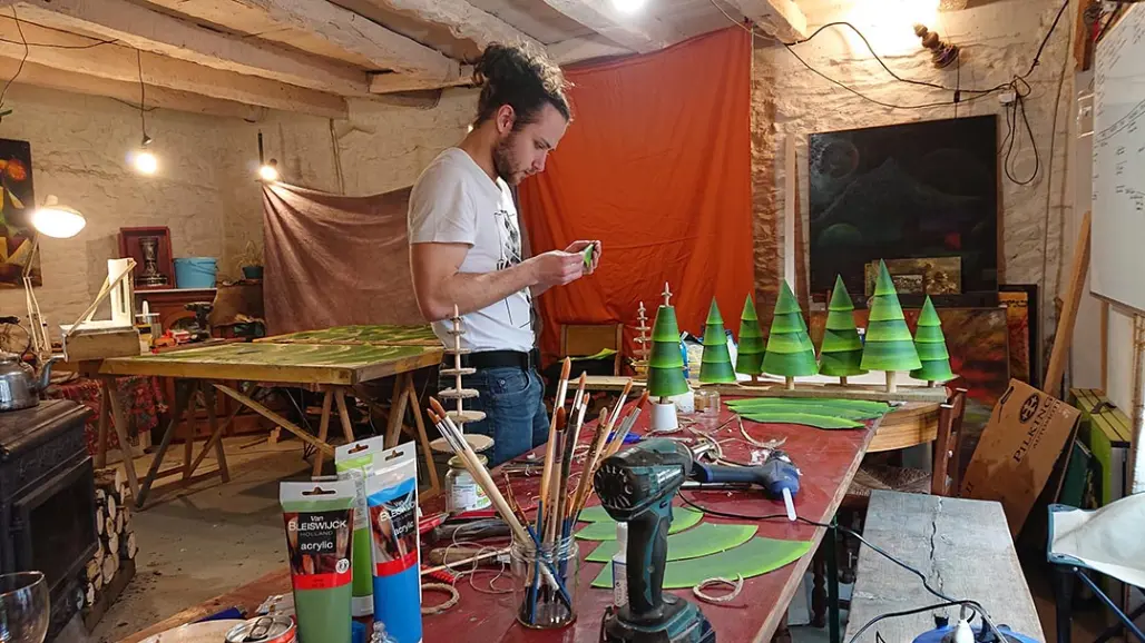 Une personne assemble des sapins en papier peints en vert